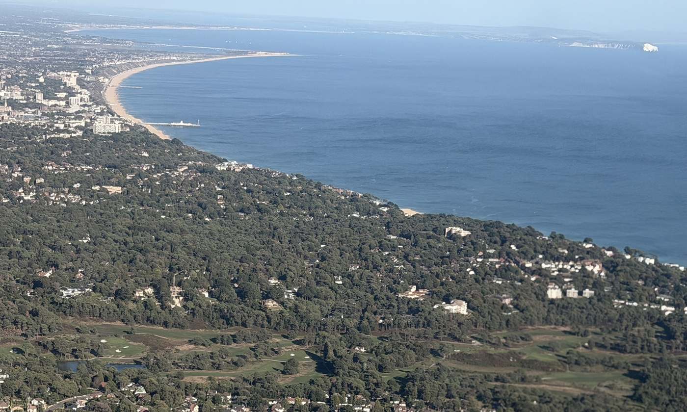 Aerial view of the coast running east from Poole towards Bournemouth, with the Isle of Wight on the horizon